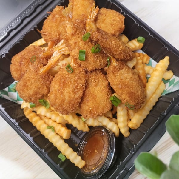 Crispy fried shrimp and crinkle-cut fries in a black takeout container with a side of sauce.