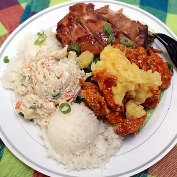 A Hawaiian plate lunch with grilled chicken, macaroni salad, rice, and orange chicken with pineapple.