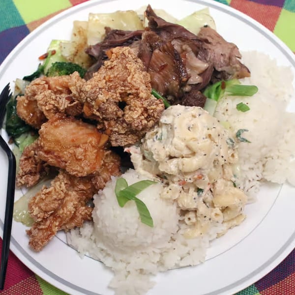 A Hawaiian plate lunch with fried chicken, kalua pig, macaroni salad, rice, and vegetables.