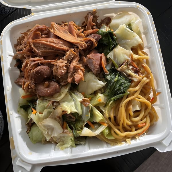 Hawaiian plate lunch with shredded pork, stir-fried cabbage, and noodles in a white takeout container.
